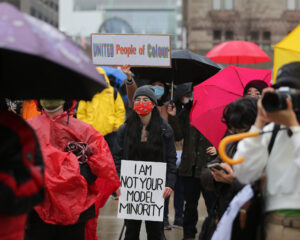 An Asian demonstrator at Nathan Phillips Square holds a sign that reads 'I am not your Modal Minority' during an anti-Asian hate rally that drew hundreds who gathered socially distanced outside of City Hall in March 2021.