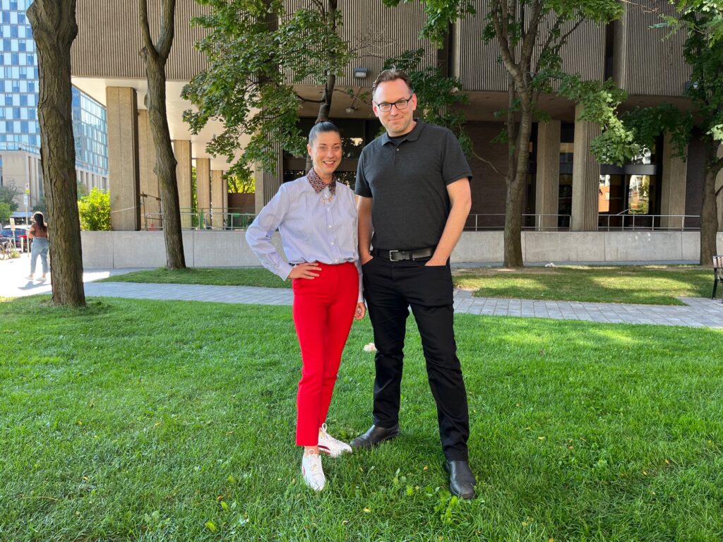 photo of Chantal Cory and Sean Kinnear in the Bloor-Bedford Parkette, with the OISE building and Bloor Street in the background