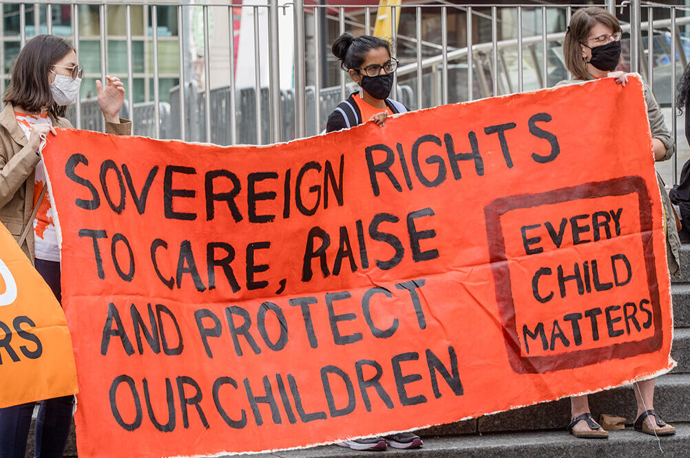 TORONTO, ONTARIO, CANADA - 2021/09/30: Participants hold a banner during the Orange Shirt Day and National Day of Truth and Reconciliation at Dundas Square, to heal, raise awareness and rise together as an Indigenous Community. Organized by Matriarchal Circle, a Toronto-based grassroots organization impacted by child welfare agencies. The Matriarchal Circle's vision is for child welfare to be practiced in Toronto in true Indigenous grassroots led circles, "as opposed to the neo-colonial, oppressive, genocidal acts in the current child welfare system. (Photo by Shawn Goldberg/SOPA Images/LightRocket via Getty Images)