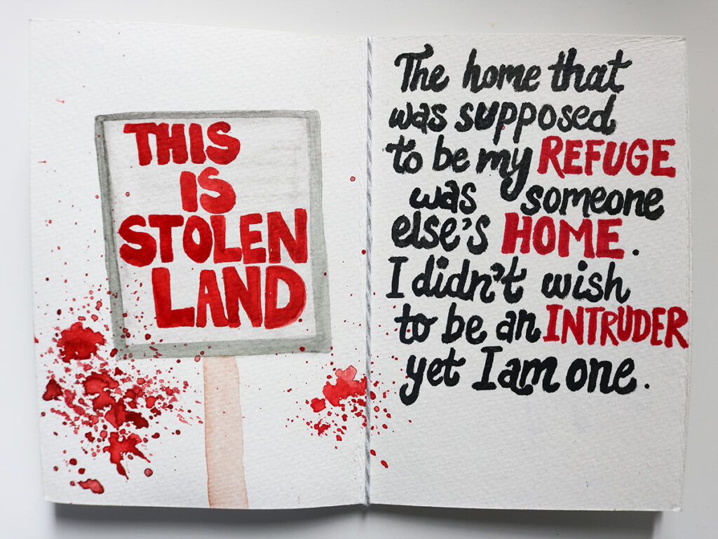 Text: "This is stolen land" written in red on a placard with splatters of red that look like blood below it. Text in black and red on the right page: "The home that was supposed to be my refuge was someone else's home. I didn't wish to be an intruder yet I am one." 
