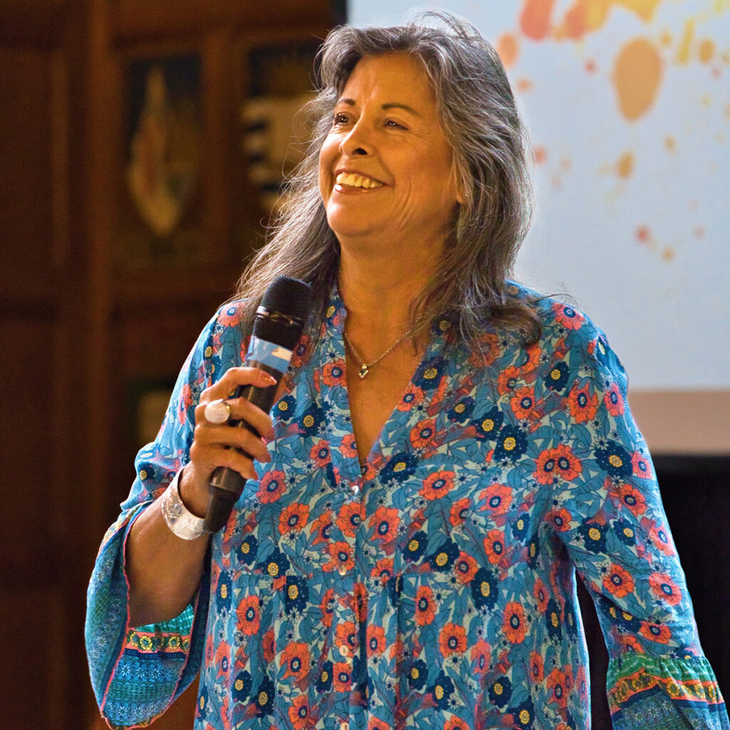 Dr. Cynthia Wesley-Esquimaux holding a microphone in Hart House's Great Hall