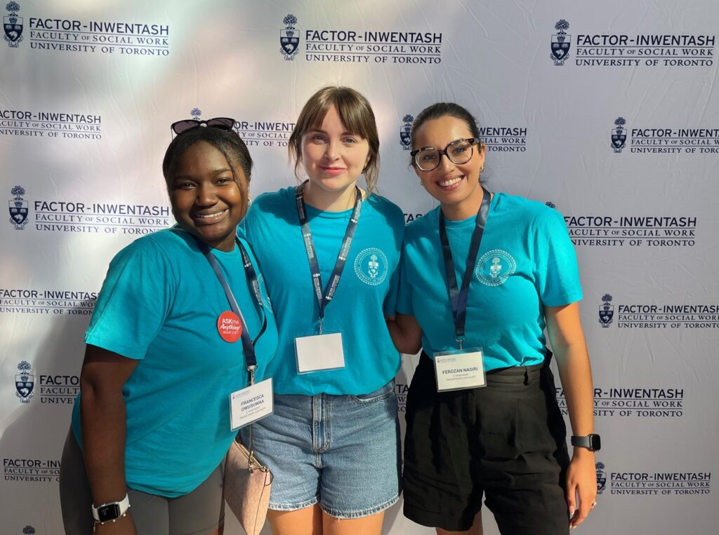 three FIFSW student ambassadors pose in front of FIFSW's stop-and-repeat