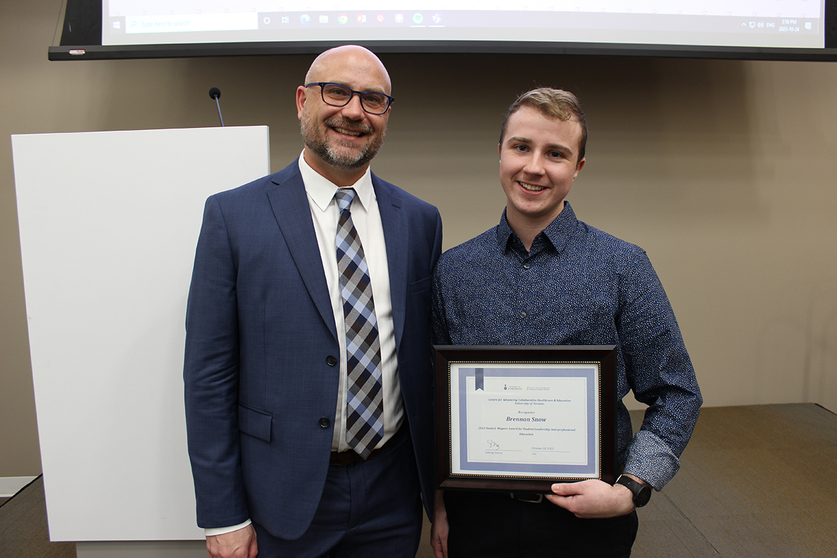 Micheal Shier and Brennan Snow. Brennan is holding a framed certificate of his award. 