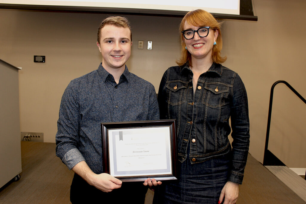 Brennan Snow, holding a framed certificate of his award, poses with Rachelle Ashcroft