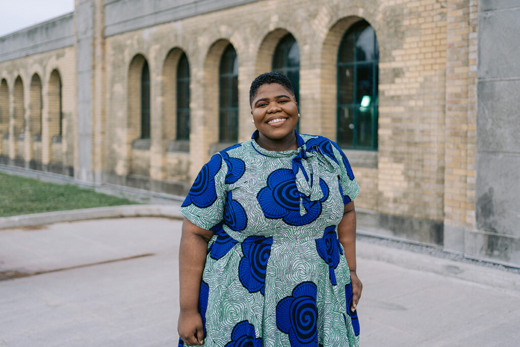 Joelle Forbes poses for a photo outdoors in front of a historic building.