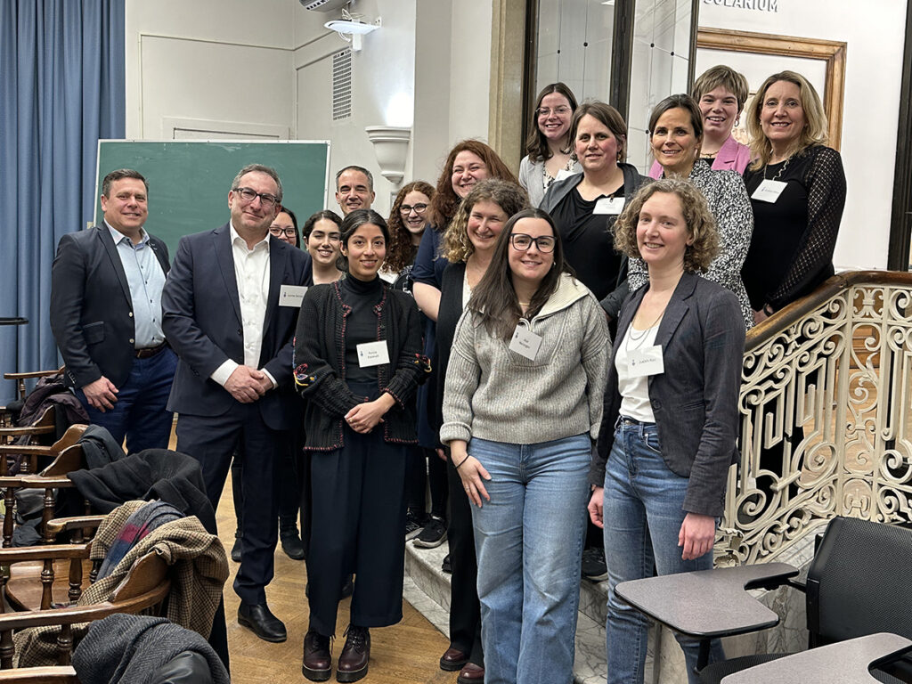 16 alumni and faculty from U of T's Law and Master of Social Work program pose for a photo at a networking event.