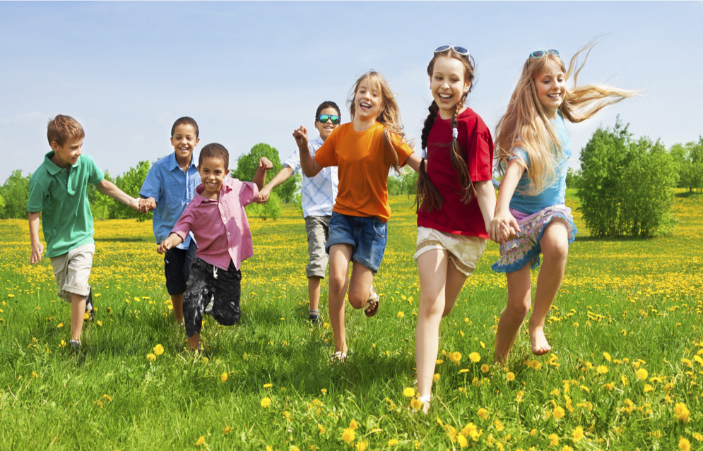 Children running through a field laughing on a sunny day
