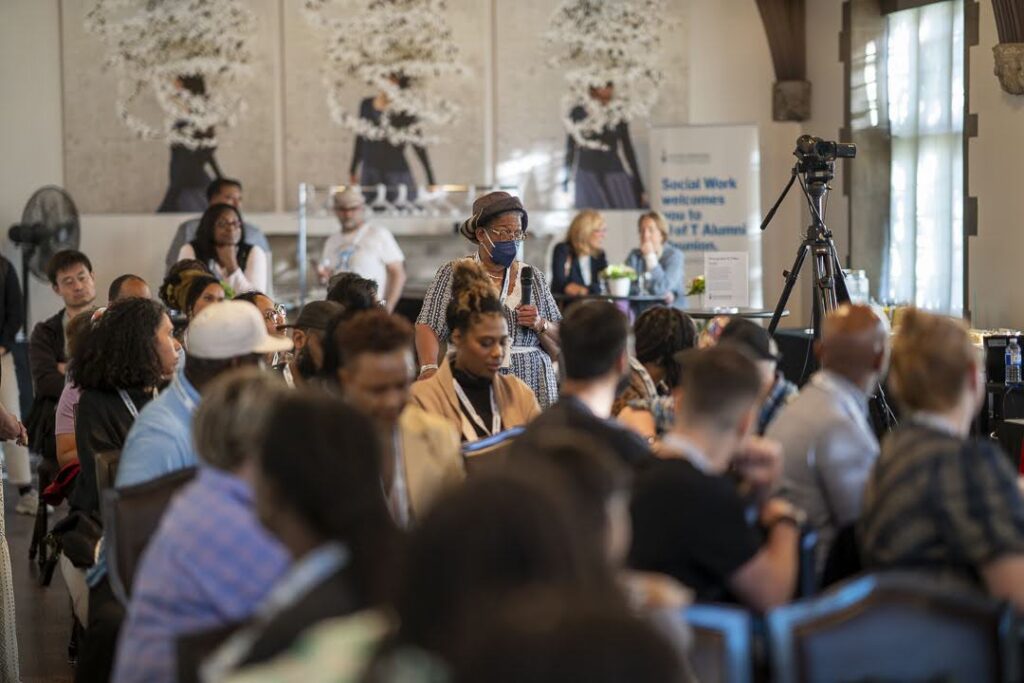 a woman from the audience stands to ask a question during an alumni event