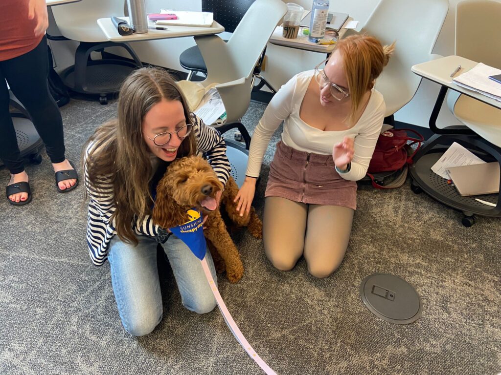 One students jugs a dog while another looks on