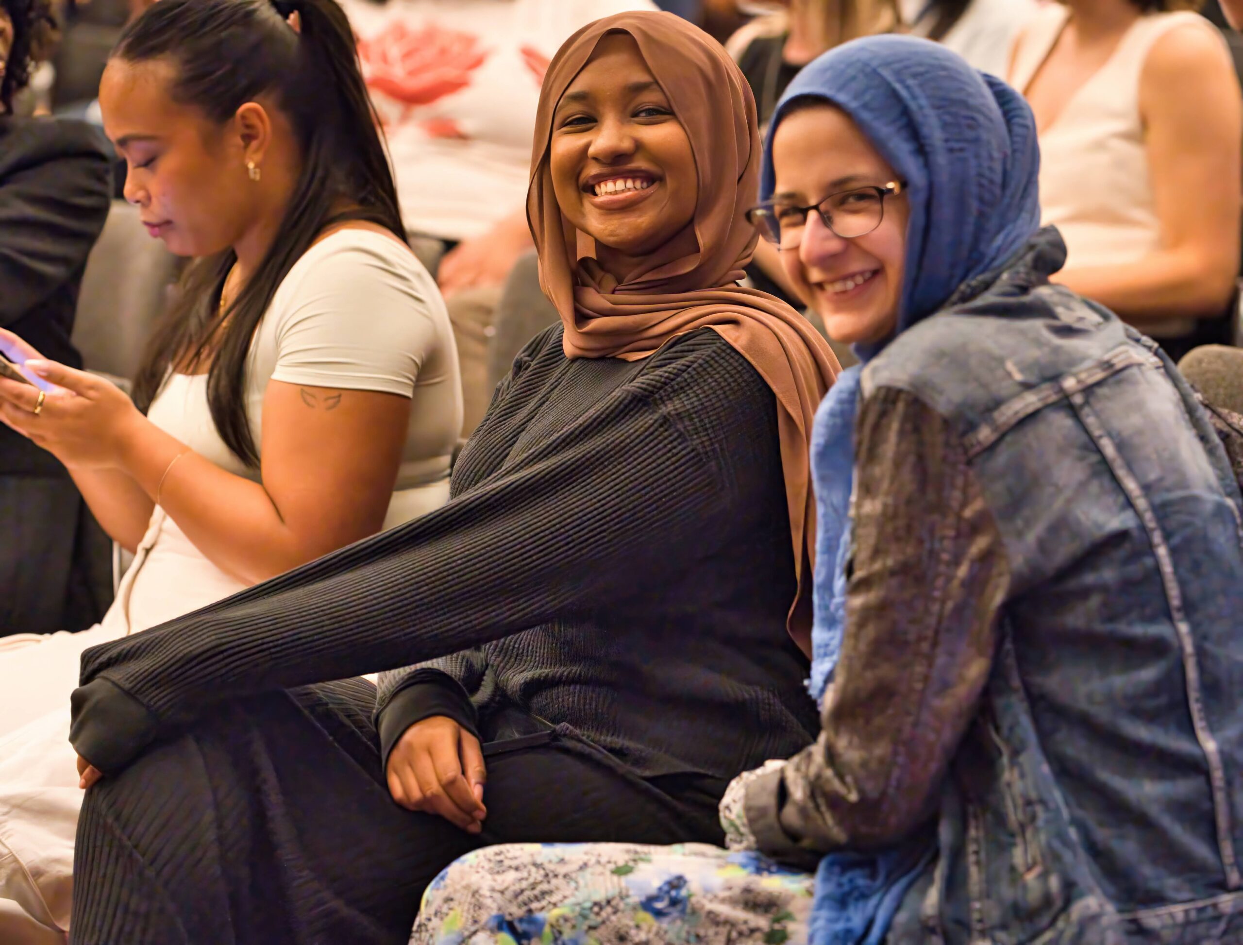 two students pose for a photo while seated at a conference