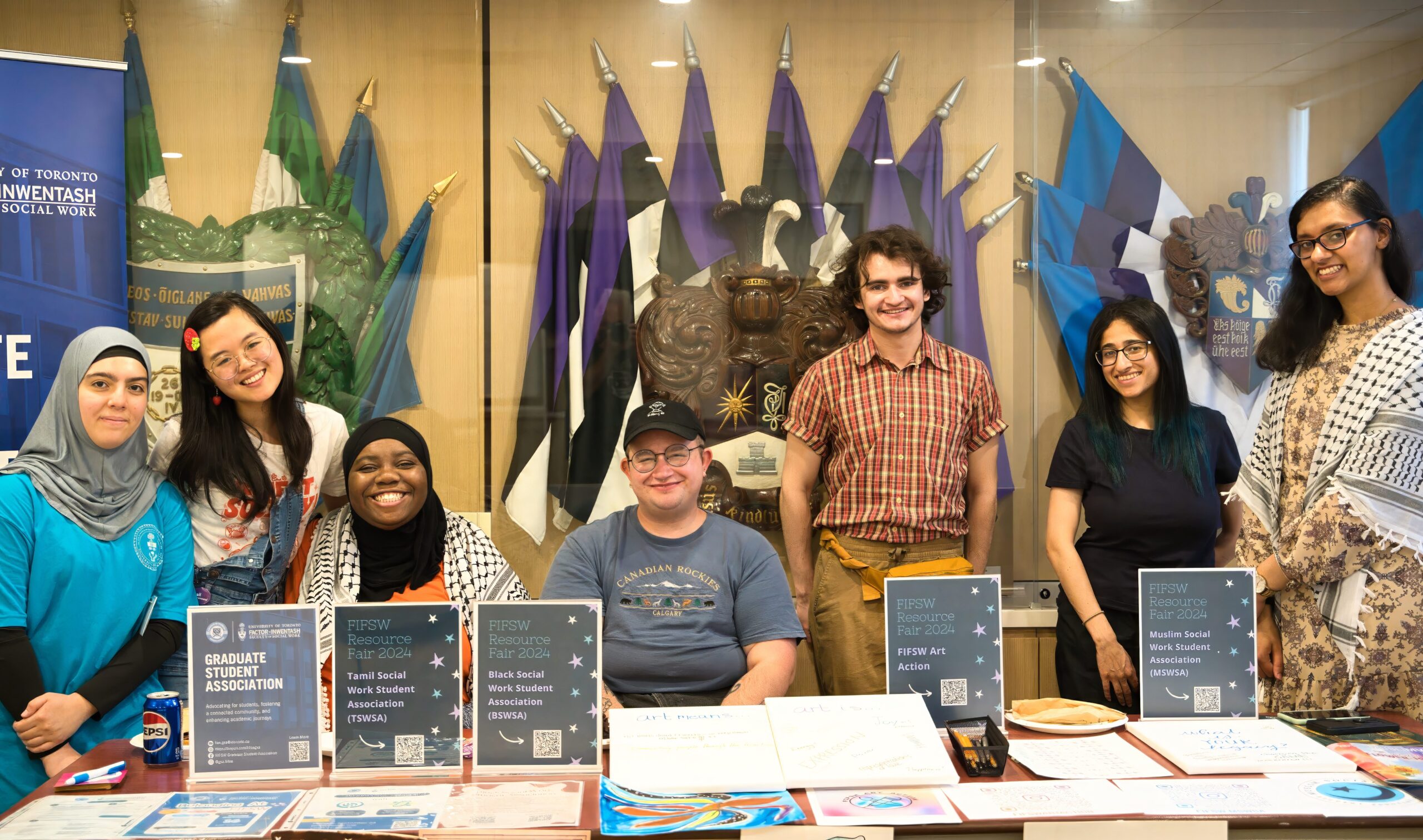 7 student representatives pose for a photo behind a table with materials about various student groups