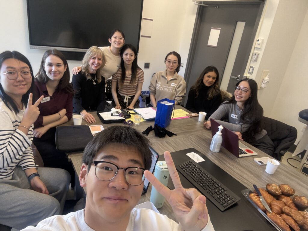 group photo of 8 practicum students sitting around a table with their field instructor and faculty-field liaison.